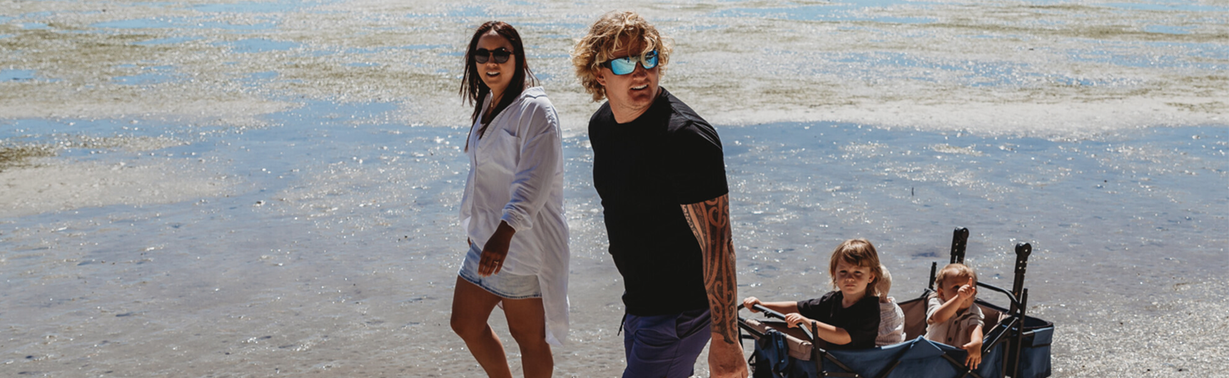 Family walking on beach - kids in cart