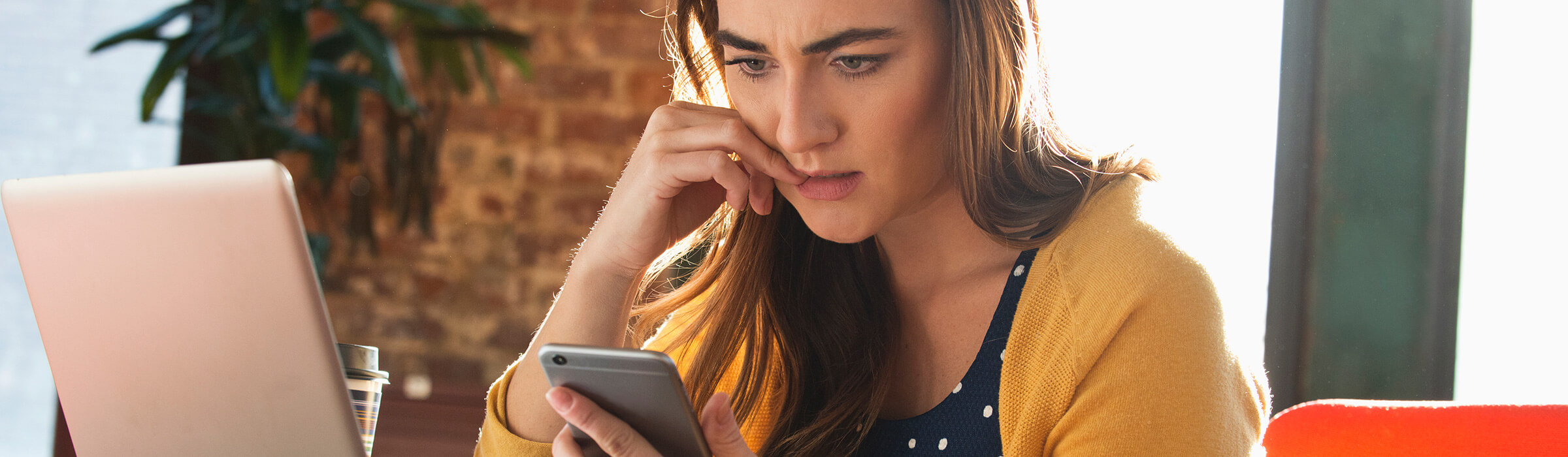Southern Cross - A woman anxiously looks at her phone while at her desk A woman anxiously looks at her phone while at her desk