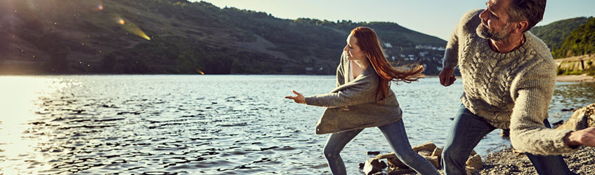 A man and woman skimming stones on a lake
